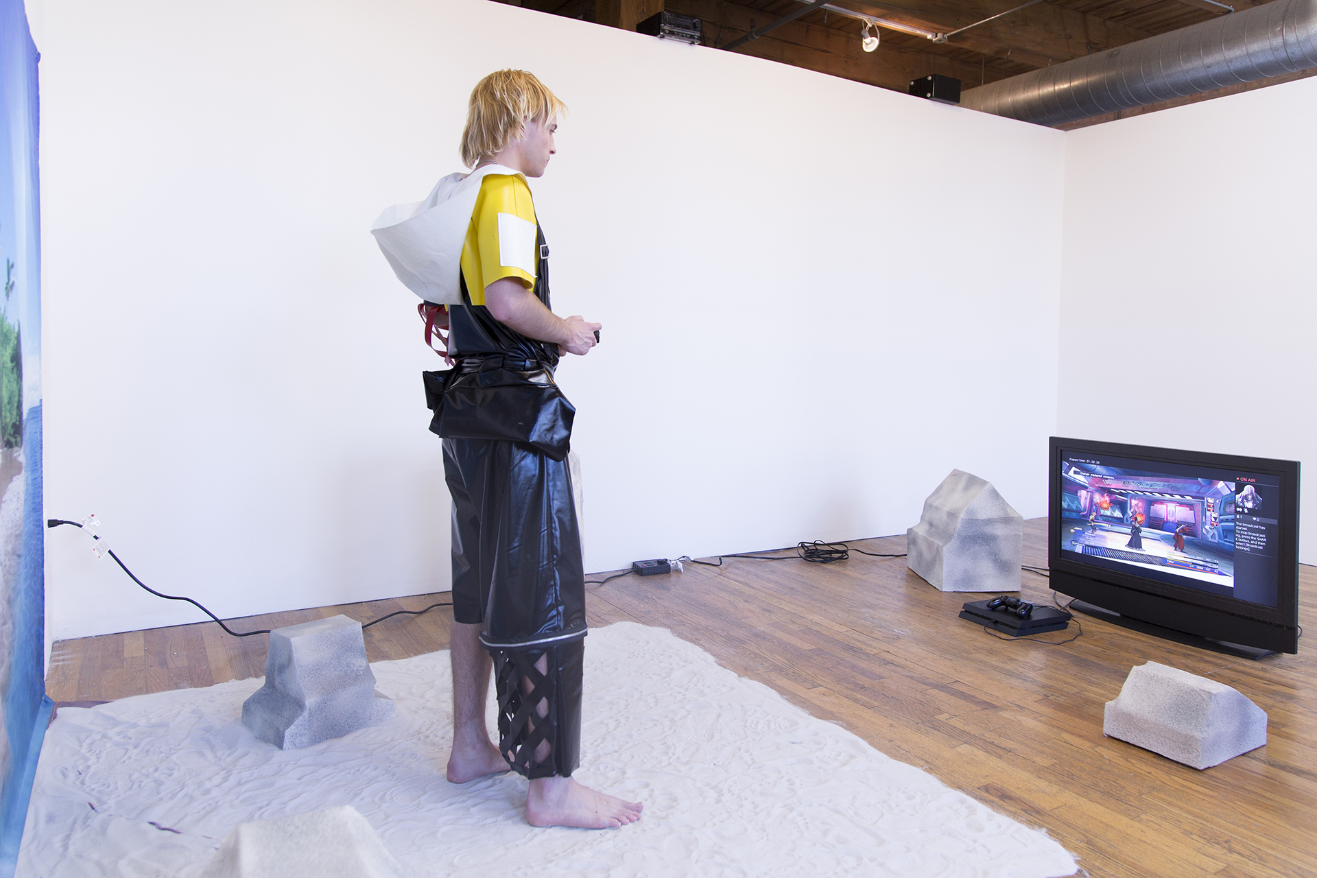Back shot of Jesse dressed in cosplay playing video games on an artificial beach set